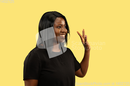 Image of Young african woman isolated on yellow studio background, facial expression