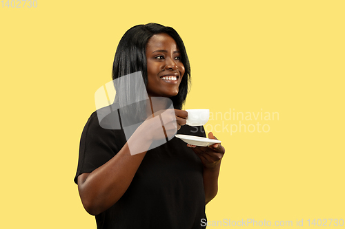 Image of Young african woman isolated on yellow studio background, facial expression