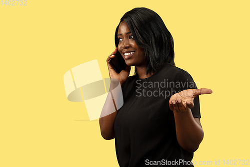 Image of Young african woman isolated on yellow studio background, facial expression