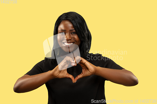 Image of Young african woman isolated on yellow studio background, facial expression