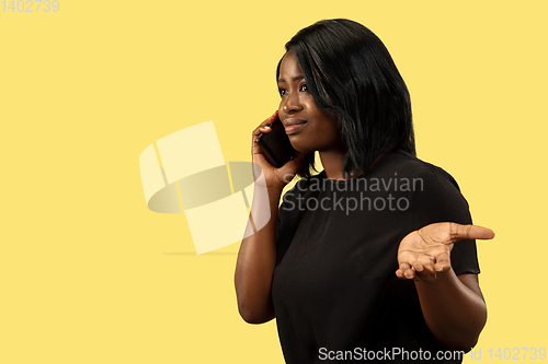 Image of Young african woman isolated on yellow studio background, facial expression