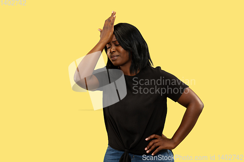 Image of Young african woman isolated on yellow studio background, facial expression