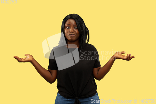 Image of Young african woman isolated on yellow studio background, facial expression