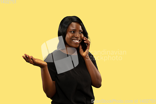 Image of Young african woman isolated on yellow studio background, facial expression