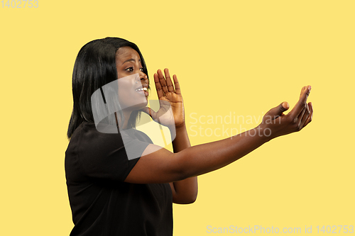 Image of Young african woman isolated on yellow studio background, facial expression