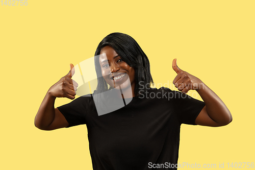 Image of Young african woman isolated on yellow studio background, facial expression