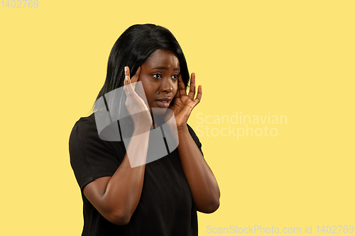 Image of Young african woman isolated on yellow studio background, facial expression