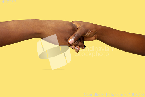 Image of Close up shot of human holding hands isolated on yellow studio background.