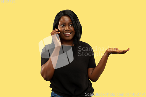 Image of Young african woman isolated on yellow studio background, facial expression