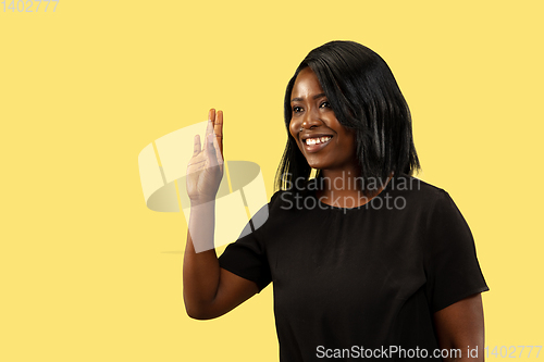 Image of Young african woman isolated on yellow studio background, facial expression