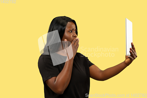 Image of Young african woman isolated on yellow studio background, facial expression