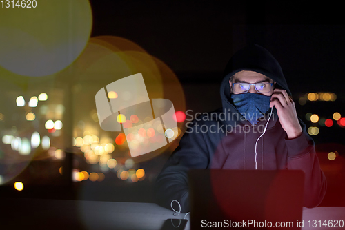 Image of hacker using laptop computer while working in dark office