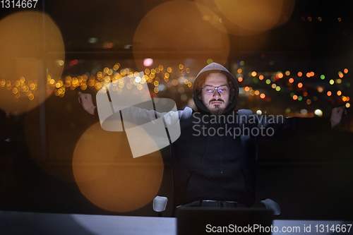 Image of hacker using laptop computer while working in dark office