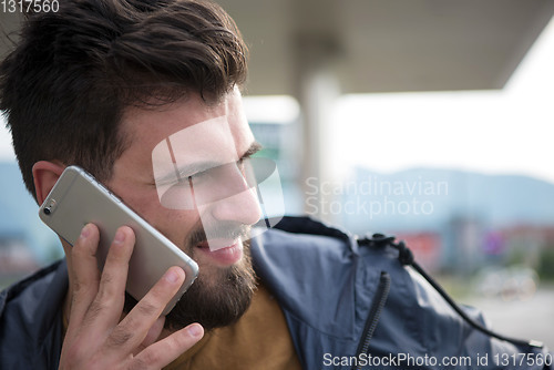 Image of handsome young casual business man with beard using cell phone