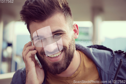Image of handsome young casual business man with beard using cell phone