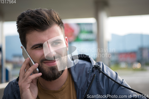 Image of handsome young casual business man with beard using cell phone