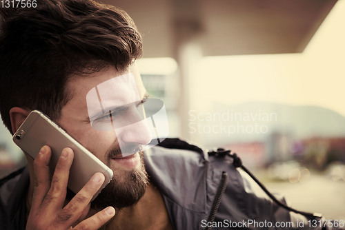 Image of handsome young casual business man with beard using cell phone