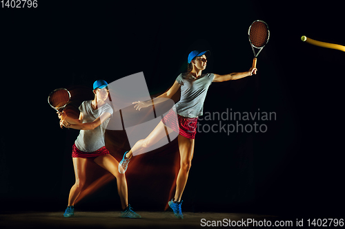 Image of One caucasian woman playing tennis on black background in mixed light