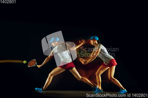 Image of One caucasian woman playing tennis on black background in mixed light