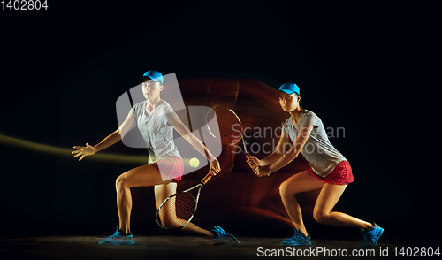 Image of One caucasian woman playing tennis on black background in mixed light