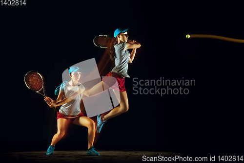 Image of One caucasian woman playing tennis on black background in mixed light