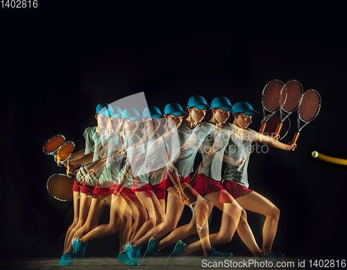 Image of One caucasian woman playing tennis on black background in mixed light