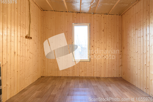 Image of The interior of a small empty room in a country house, the walls are clapboard, linoleum is laid on the floor