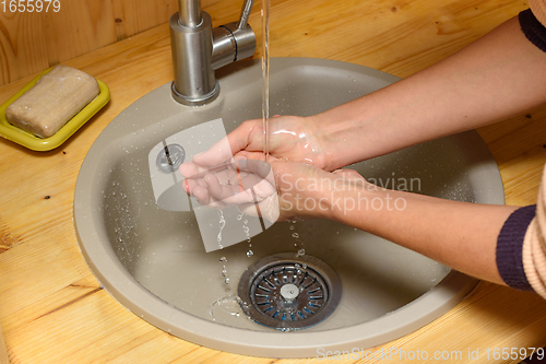 Image of The girl\'s hands wash their hands in the sink set on a wooden tabletop