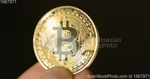 Image of Shiny physical bitcoin in hands over sunlight
