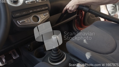 Image of Man cleaning dirty car interior with vacuum cleaner