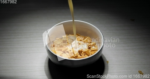 Image of Pouring milk into bowl of cereal closeup