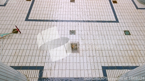 Image of Steel drain on tiled floor with water whirling