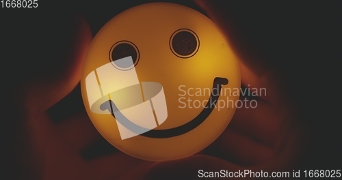 Image of Hands holding glowing smiley head closeup footage