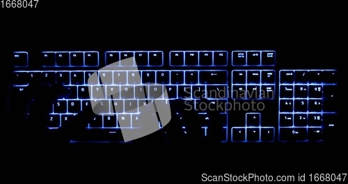 Image of Hands typing in the dark on illuminated keyboard