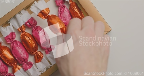 Image of Man and woman picking out christmas chocolate from box