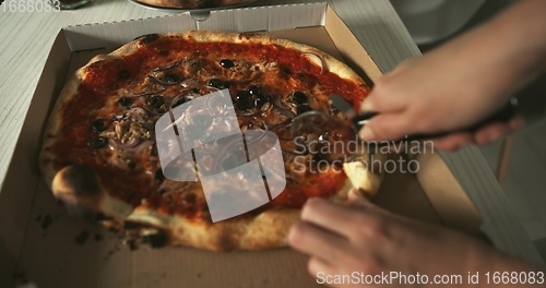 Image of Delicious pizza being sliced up on the table