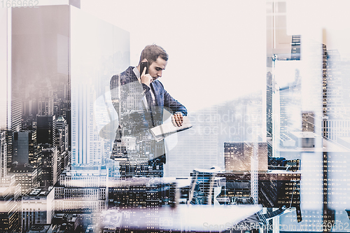 Image of Businessman talking on mobile phone while looking at wristwatch.