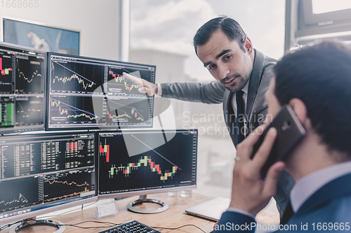 Image of Stock brokers looking at computer screens, trading online.