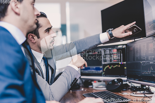 Image of Stock brokers looking at computer screens, trading online.