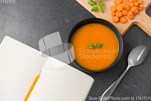 Image of close up of pumpkin cream soup and notebook