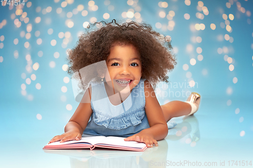 Image of smiling little african american girl reading book