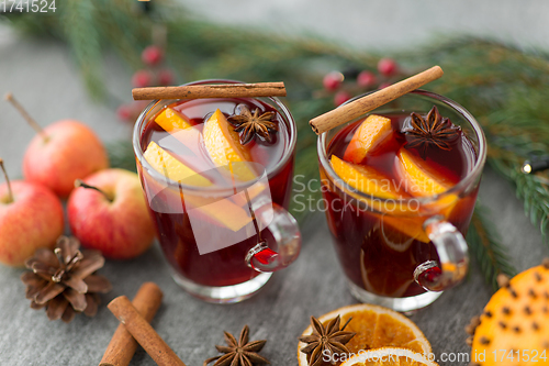 Image of glass of hot mulled wine, cookies, apples and fir