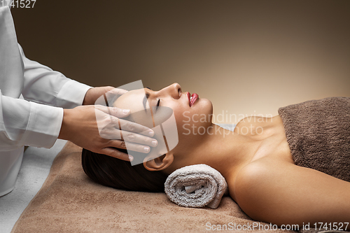 Image of woman having face and head massage at spa