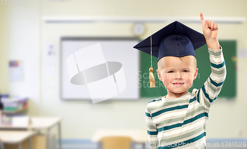 Image of boy in mortar board pointing finger up at school