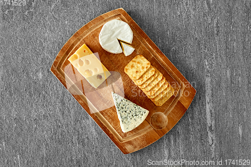 Image of different cheeses and crackers on wooden board