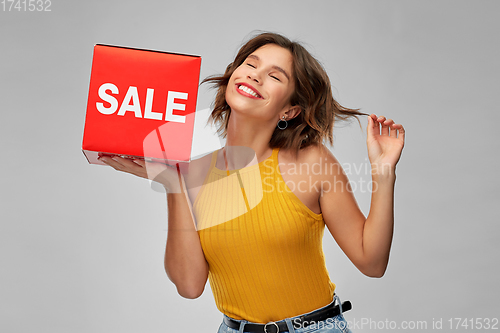 Image of happy smiling young woman posing with sale sign