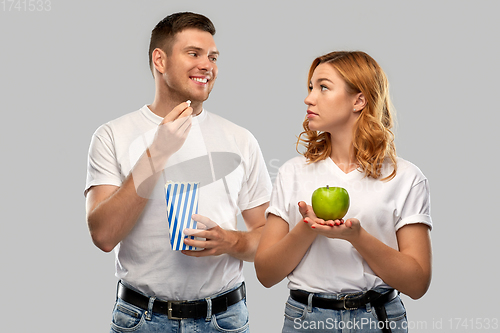 Image of couple in white t-shirts with popcorn and apple