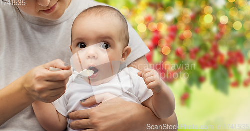 Image of close up of mother with spoon feeding little baby