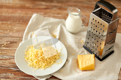 Image of close up of grated cheese and jug of milk on table