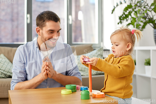 Image of father playing with little baby daughter at home